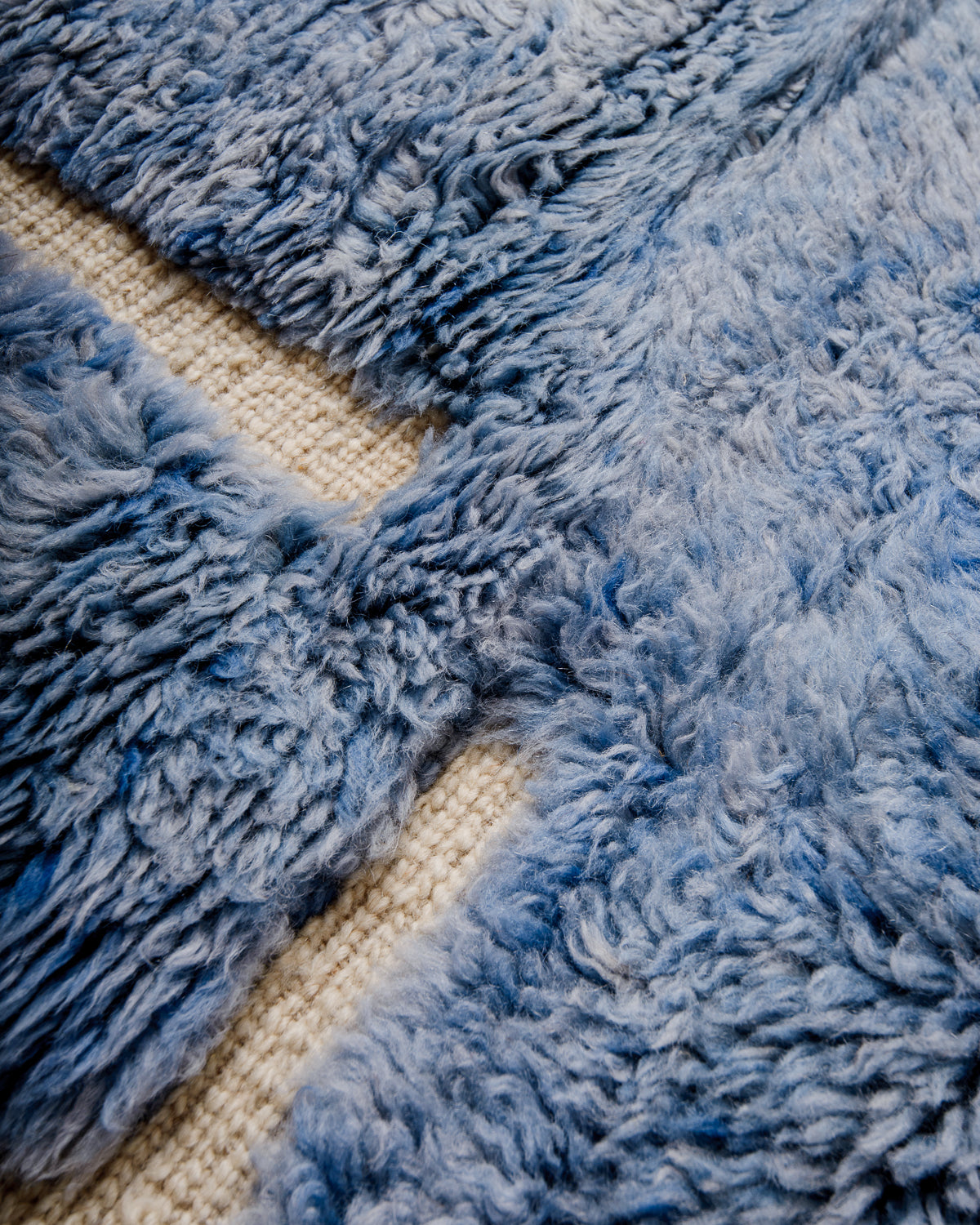 Detail of Beni M'rirt rug showing thick wool pile in blue and woven cream design.